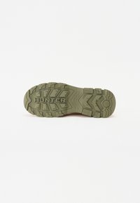 Talpa de cauciuc verde cu modele adânci de tread și marcaj ridicat "HUNTER" pentru aderență și durabilitate.