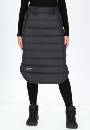 Gevoerde zwarte rok met een gewatteerd ontwerp, met een ronde zoom en zijzakken. Gepaard met zwarte leggings en laarzen.