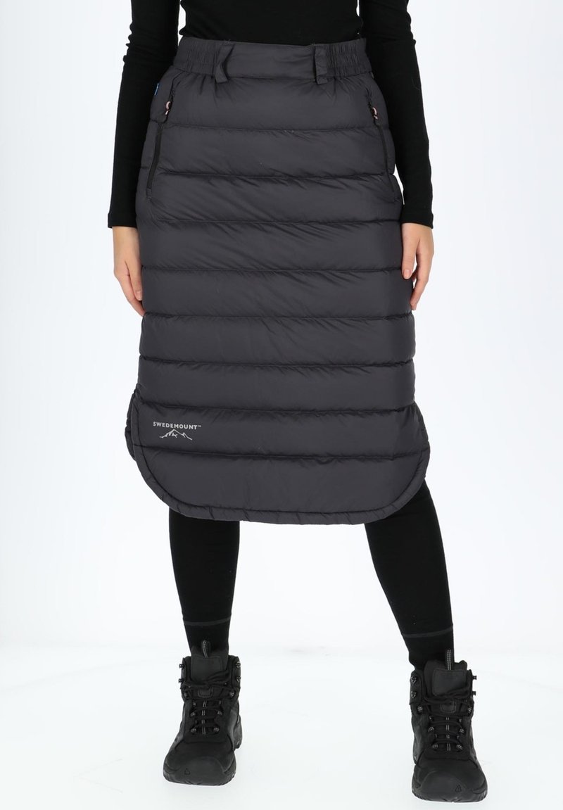 Padded black skirt with quilted design, featuring a rounded hem and side pockets. Paired with black leggings and boots.