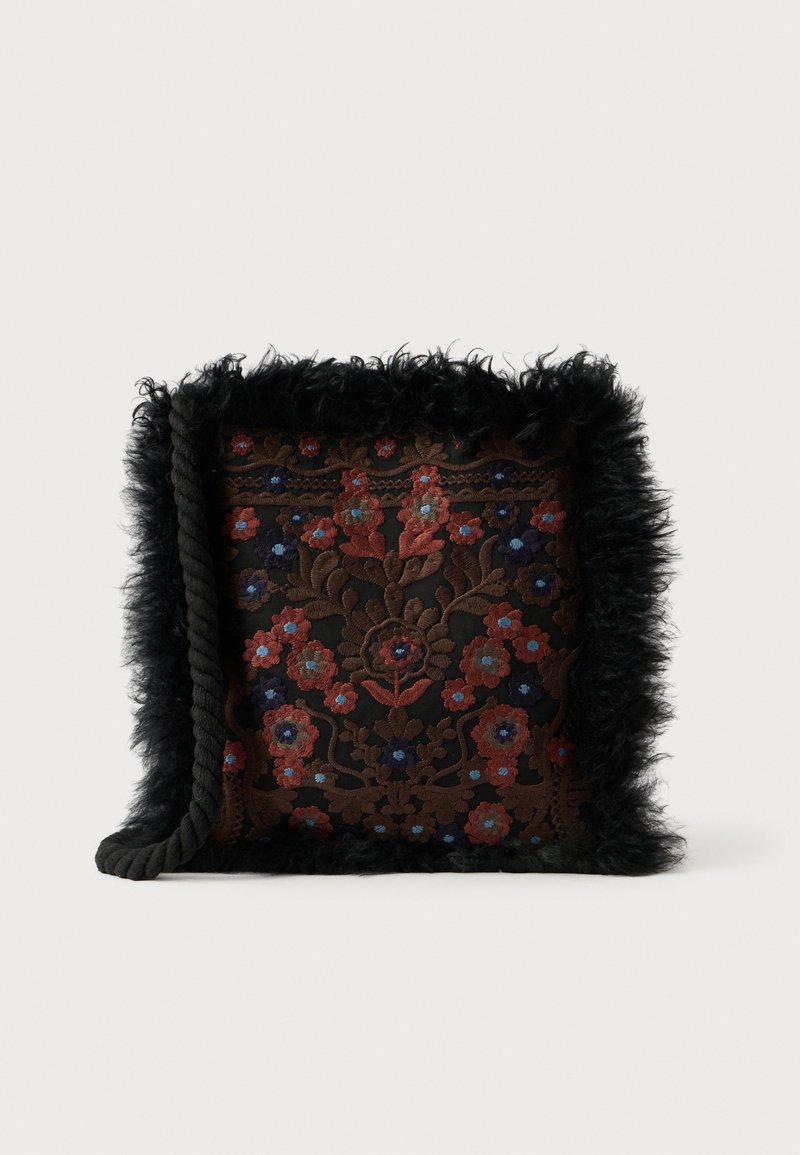 Čierna taška s kožušinovou obrubou zdobená zložitou kvetinovou výšivkou v červenej, modrej a hnedej farbe na tmavom pozadí. Pletená rukoväť na jednej strane.
