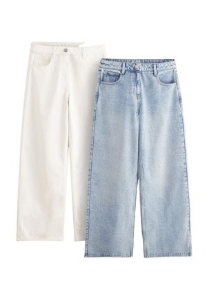 Bílé široké kalhoty z bavlny a světle modré džíny širokého střihu, oboje s kapsami, knoflíky a uvolněným střihem, vystavené vedle sebe.