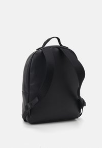 Zaino in pelle nera con una texture a granulato, spallacci regolabili, forma arrotondata e una maniglia superiore per il trasporto.
