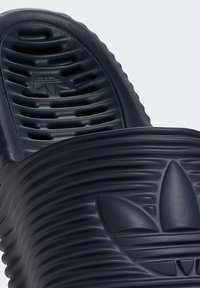 Navy blue slide sandal with ribbed texture, featuring vented upper and embossed logo. Made of durable synthetic material, ergonomic design.