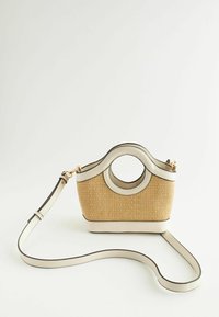 Petit sac à main beige tissé avec découpe circulaire pour la poignée et bandoulière réglable, présenté sur fond blanc uni.