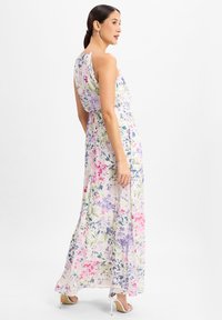 Maxi-jurk van lichte stof met een bloemmotief in roze, paars en groene tinten, mouwloos ontwerp en een strikdetail in de taille.