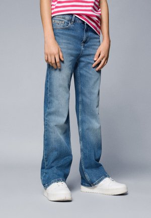 Lys blå denimbukser med løs pasform, falmet tekstur, lige ben-design og fem-lomme stil, parret med hvide sneakers.
