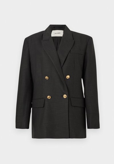Blazer nero doppiopetto con bottoni dorati, colletto a punta e due tasche frontali; tessuto intrecciato con una texture liscia. Etichetta del marchio visibile all'interno.