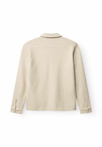 Béžová košile s dlouhými rukávy a límečkem, textura látky a rukávy s knoflíky. Má rovný střih a jemné švy.