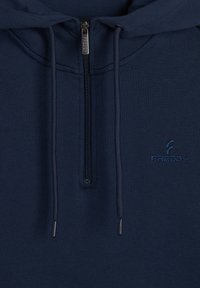 Felpa con zip di colore blu navy realizzata in tessuto morbido, dotata di un colletto alto, cordini e un discreto logo ricamato. Texture liscia con un design pratico.