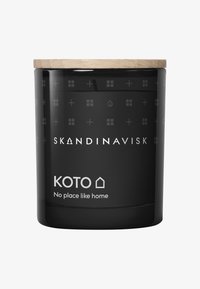 Svart ljushållare med trälock, prydd med präglade mönster av fönster och symboler. Etiketten säger "KOTO Inga ställen som hemma."