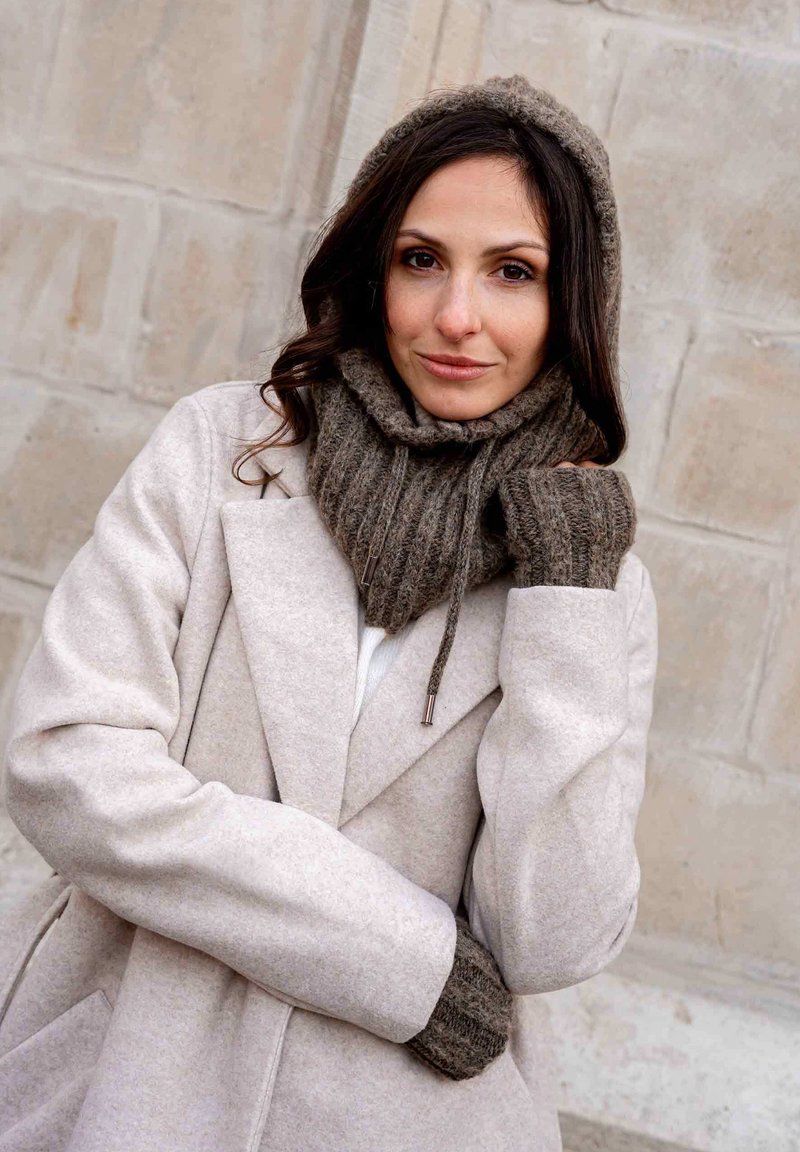 Light gray wool coat with a wide collar, paired with a dark knitted scarf and fingerless gloves. Textured fabric details are visible.