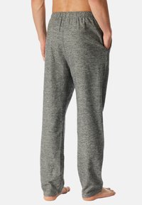 Grå, löst sittande sweatpants i mjukt tyg, med ett elastiskt midjeband och sidofickor, sedd bakifrån.