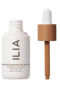 Vit glasflaska med ett brunt dropparkap, märkt "Super Serum Skin Tint SPF 30", vilket indikerar en lätt, tonad serumformulering.