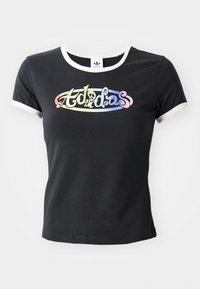 Sort bomulds T-shirt med hvid ribbet krave og ærmer. Har et farverigt, stiliseret "Adidas" logo på forsiden.
