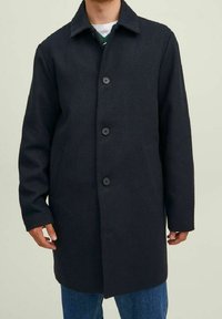 Cappotto di lana blu scuro con colletto, chiusura a bottoni monopetto e tasche laterali. Presenta una linea dritta e un materiale strutturato.