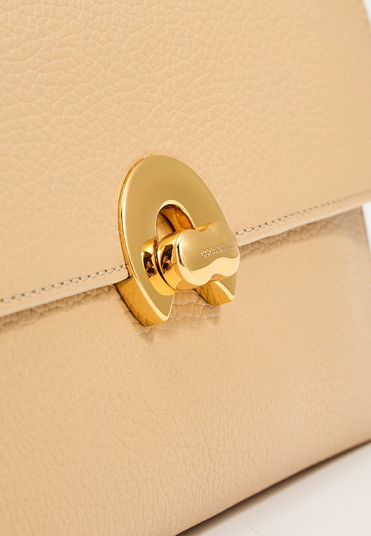 Borsa a mano in pelle beige con una finitura texturizzata, caratterizzata da una evidente chiusura in metallo dorato e bordi cuciti per un tocco di dettaglio.