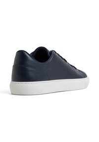 Sneaker in pelle blu navy con una texture liscia, suola in gomma bianca, punta rotonda e design minimalista. Presenta lacci e cuciture sottili.