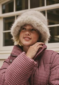 Rosa gesteppte Daunenjacke mit oversized grauem Pelzhut. Die Jacke verfügt über ein strukturiertes Muster und einen großen Kragen mit Druckknopfverschluss.