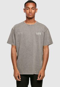 Grå oversized t-shirt lavet af blødt, tekstureret stof. Har en rund hals og trykt "LIFE" detalje på fronten.