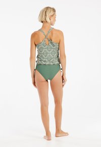 Grönmönstrad tankini överdel med design i nyckelhål bak, ihop med enfärgad grön bikiniunderdel. Lugn och avslappnad passform med mjuk textur.