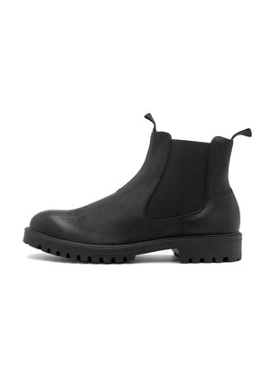 Botas Chelsea negras con paneles laterales elásticos, punta redondeada, cuero vegano texturizado y suela de goma gruesa con patrones de relieve profundos.