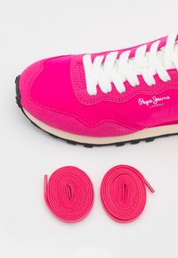 Rosa mockaskor med vita snören, svart sula och "Pepe Jeans London"-logotyp. Två matchande rosa skosnören ligger nedanför skon.