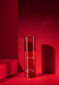 Punainen suihkepullo, jossa on läpinäkyvä korkki, ja jonka etiketissä lukee "TIRTIR MASK FIT MAKE UP FIXER." Pinnassa on kiiltävä viimeistely punaisella taustalla.