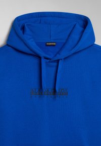 Sudadera azul con estampado de logotipo negro, capucha con cordones y tejido suave. Textura lisa con un único diseño de bolsillo frontal.