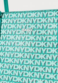 Türkiz táska, szürke DKNY logómintával, texturált anyagból, elegáns kialakítással és állítható pánttal.