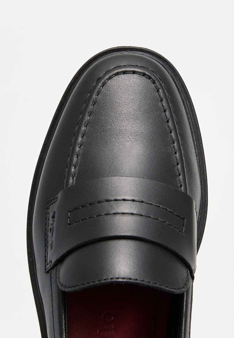 Schwarze Lederloafer mit einem breiten Riemen über dem Spann, genähten Details an der Zehenpartie und einer glatten Textur. Rote Innensohle sichtbar.