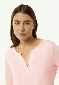 Light pink long-sleeve shirt with a V-neck and a smooth, soft texture; features a relaxed fit.