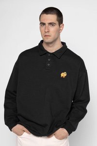 Polo a maniche lunghe nera con colletto, dotata di tre bottoni e un design di un cane arancione ricamato sul lato sinistro del petto. Materiale in cotone.