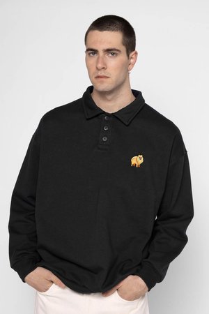 Schwarzes Langarm-Polohemd mit Kragen, ausgestattet mit drei Knöpfen und einem gestickten orangen Hundedesign auf der linken Brust. Aus Baumwollmaterial.