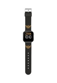 Montre numérique avec un cadran carré noir, affichage numérique blanc de l'heure, texte doré "Zelda" et un bracelet noir texturé avec un emblème doré.
