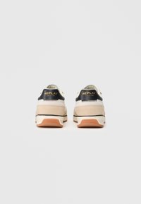 Scarpe sportive beige e nere realizzate in materiali scamosciati e mesh, con un logo sul tallone e dettagli neri. Suola in gomma con dettagli beige.