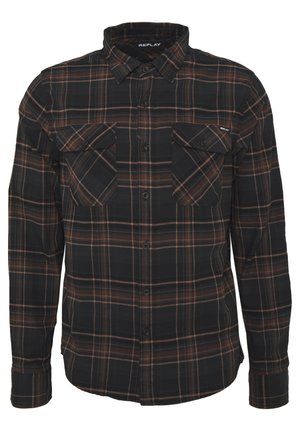 Chemise en flanelle à carreaux noirs et marron avec des manches longues, un devant boutonné et deux poches poitrine. Texture douce et design décontracté.