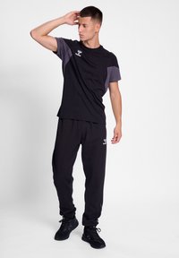 Conjunto deportivo negro que presenta una camiseta de manga corta con detalles en gris y pantalones de chándal negros. Hecho de un tejido ligero y transpirable.