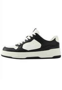 Sneaker with a black leather upper, white leather accents, and a textured white rubber sole. Designed with perforated details and thick white laces.
