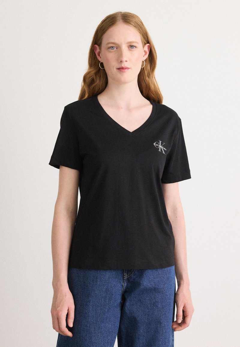 Czarny t-shirt z dekoltem w serek, wykonany z miękkiej tkaniny, z krótkimi rękawami; na lewej piersi znajduje się małe logo CK.