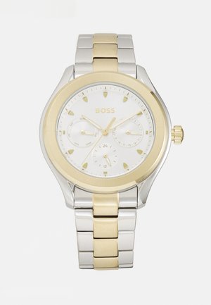 Montre argentée et dorée avec un cadran blanc. Les caractéristiques incluent trois sous-cadrans, des accents dorés et un design de bracelet à maillons.
