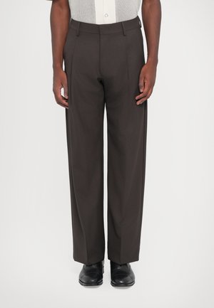 Dark brown, high-waisted trousers with a straight leg design. Made of smooth fabric, featuring belt loops and pressed creases. Black shoes worn.