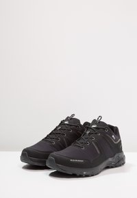 Czarne buty trekkingowe z syntetyczną cholewką, zaokrąglonym noskiem, wzmocnioną osłoną palców i teksturowaną gumową podeszwą. Zawierają szare akcenty i elementy odblaskowe.