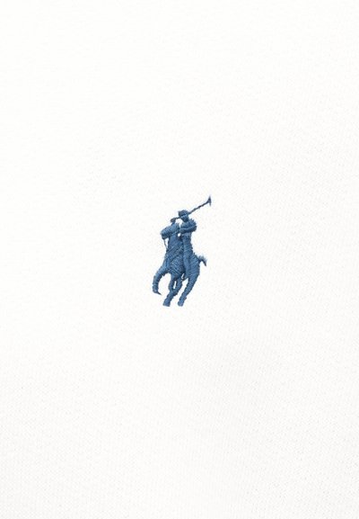 Παίκτης πόλο επάνω σε άλογο σε μέση δράση, που κουνά ένα σφυρί, κεντημένος με μπλε σε λευκό ύφασμα.