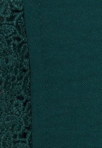 Dark teal fabric with a textured, embroidered pattern on one side and a smooth, plain finish on the other. Seams are neatly sewn.