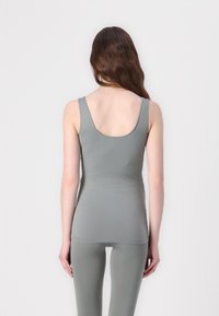 Gray ribbed tank top with a wide neckline, fitted design, and thin straps, paired with matching fitted leggings. Smooth texture.