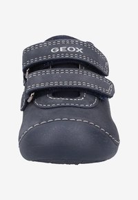 Baskets bleu marine avec deux bandes Velcro, coutures blanches contrastantes, bout arrondi et semelle en caoutchouc. Logo de la marque visible sur le dessus.