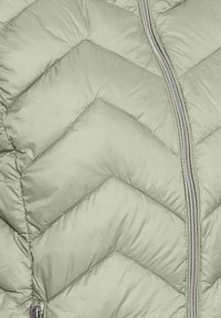 Padded Jacke in Hellgrün mit einem Zickzack-Quiltmuster. Verfügt über einen silbernen Reißverschluss und eine glatte, glänzende Stoffstruktur.