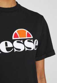 Schwarzes Baumwoll-T-Shirt mit einem großen weißen Logo und einem orange-roten geschwungenen Akzent. Mit kurzen Ärmeln und klassischem Rundhalsausschnitt.