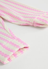 Gestreifter rosa und cremefarbener, gerippter Stoff mit wellenförmigen Kanten, der gefaltete Ärmel auf weißem Hintergrund zeigt.