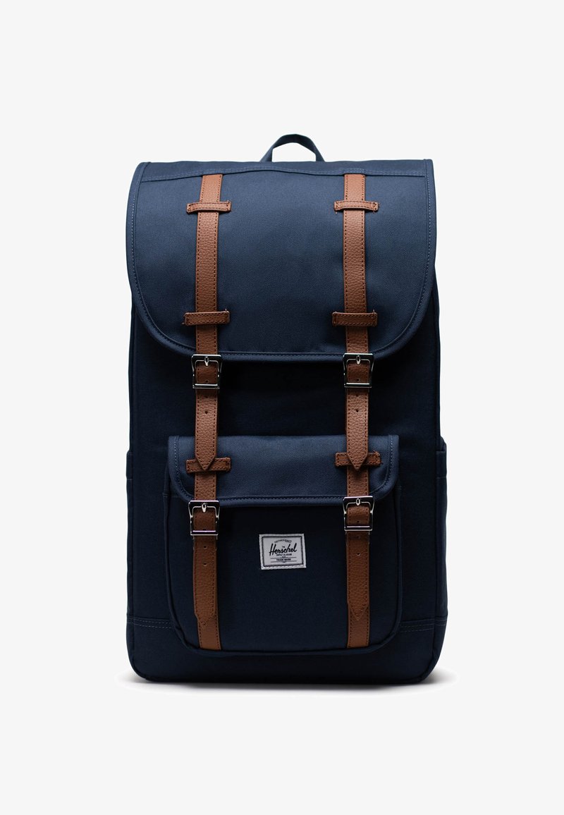 Laadon kangaskassi tummansinisellä kankaalla, ruskealla nahkahihnalla, hopeisilla yksityiskohdilla, läppäkiinnityksellä, etutaskulla ja logotarralla alareunassa.